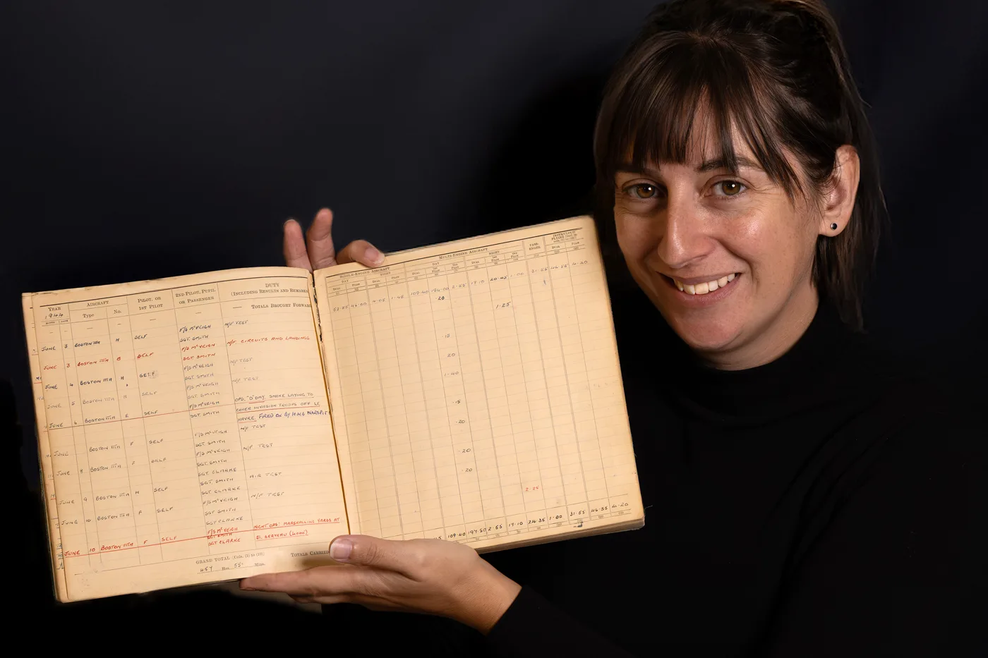 Jessica Tarver of David Duggleby Auctioneers holding open Leslie Valentine's wartime flying logbook